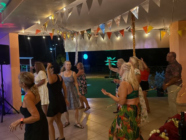 Foto real de los invitados bailando en la terraza de La Divina Commedia Coronado, bajo banderines y luces de colores